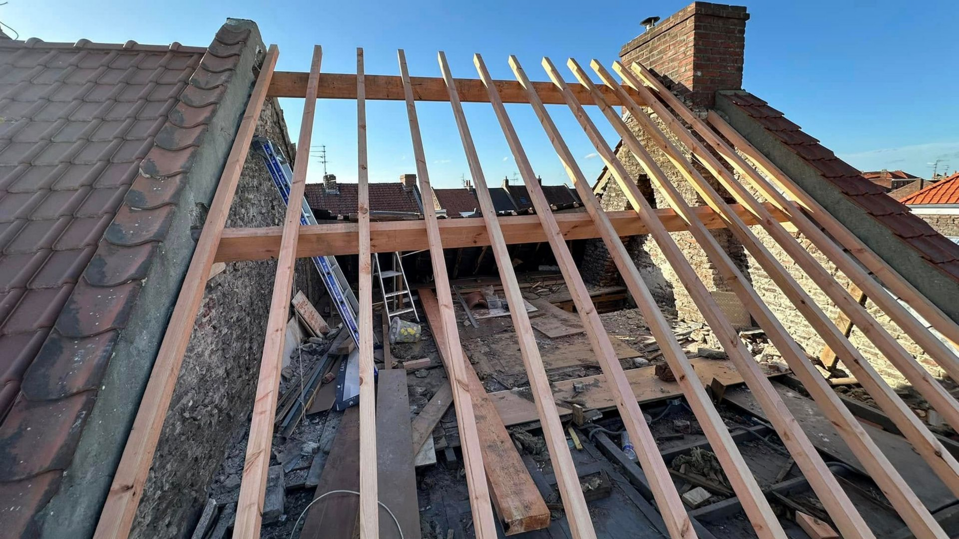 Charpente de toit en bois en construction, soutenue par des murs en parpaings.