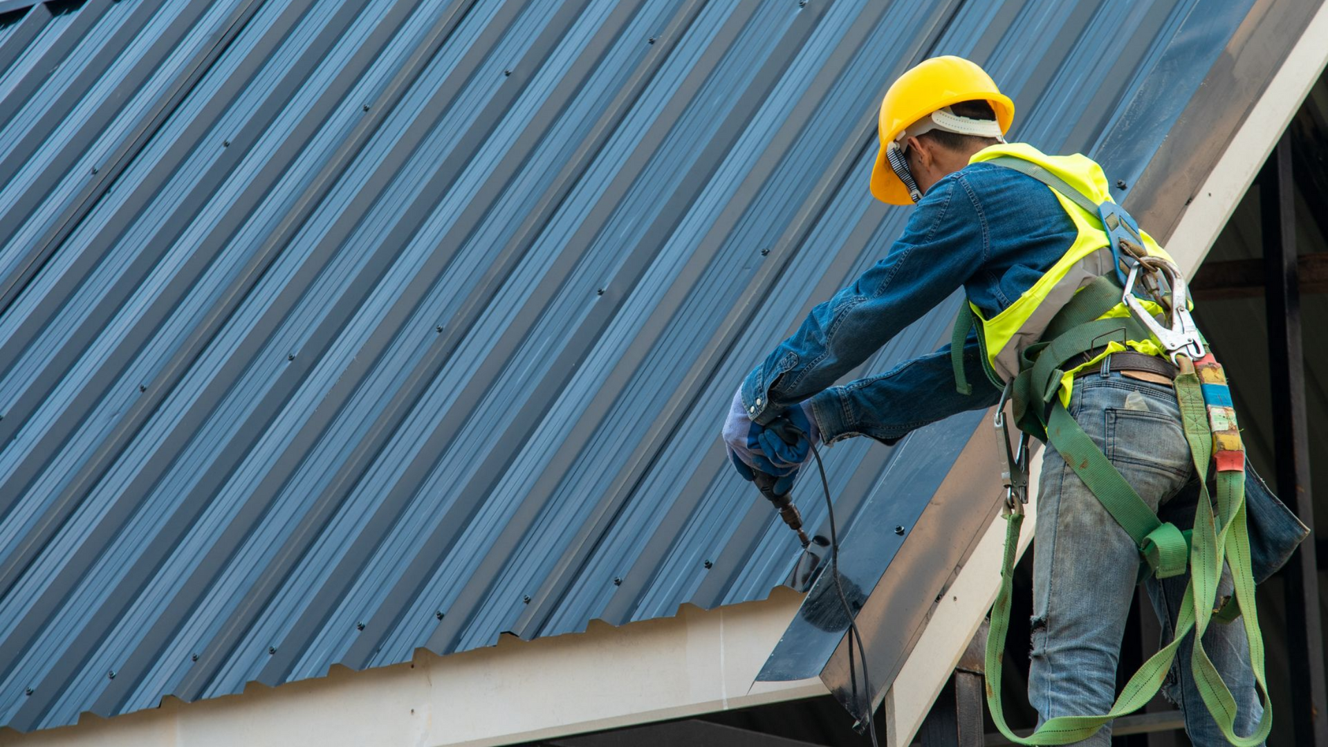 Couvreur sur un toit en métal bleu.