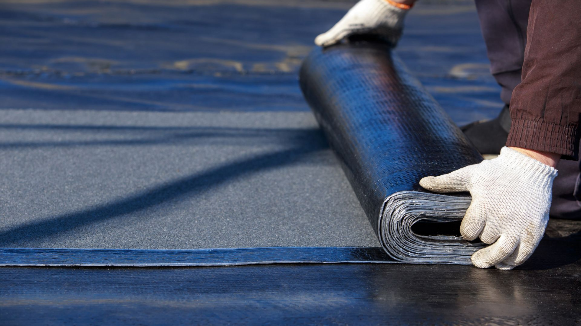 Personne déroulant un matériau de toiture.