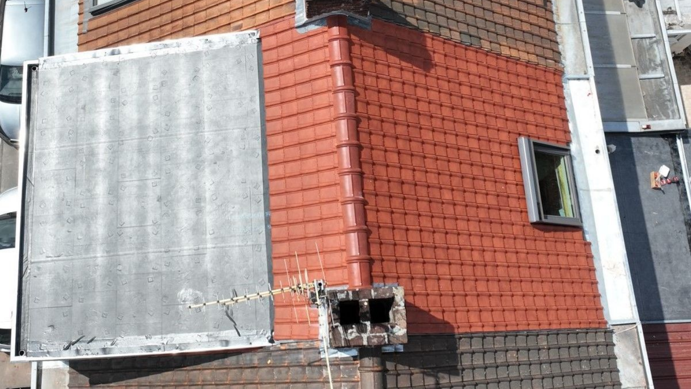 Maison en briques au toit de tuiles rouges.