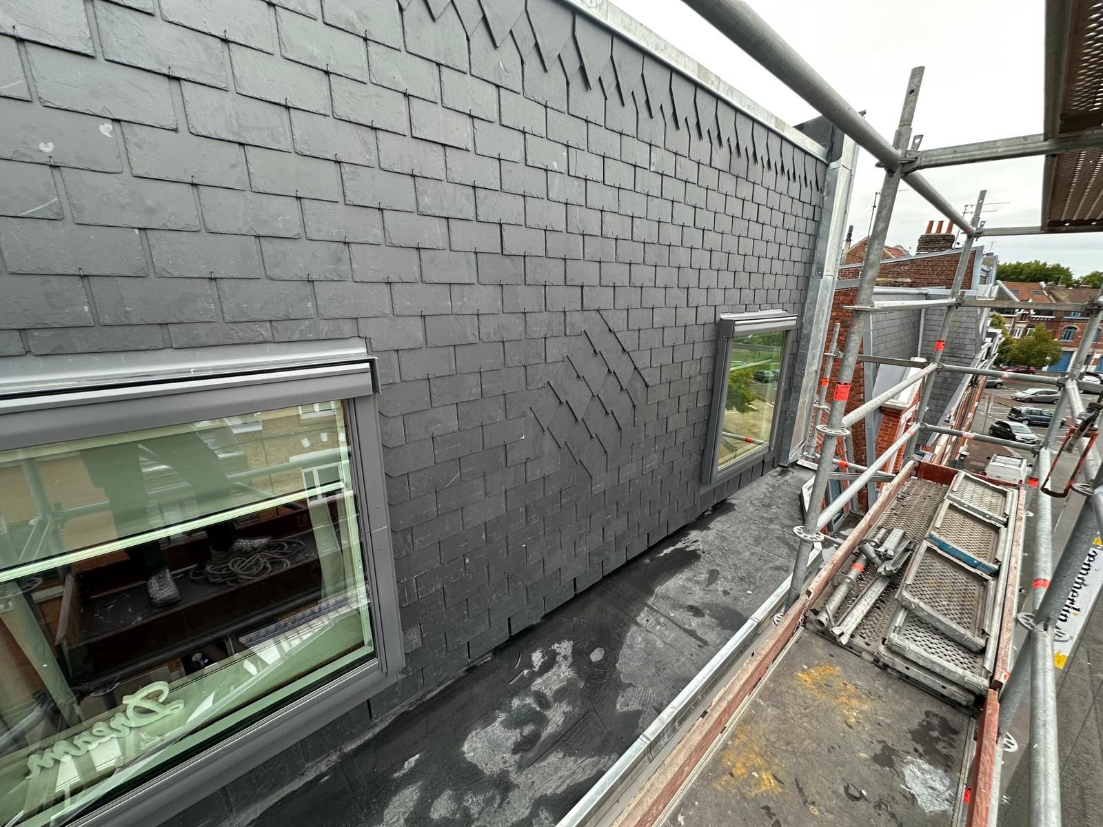 Toit plat recouvert de goudron noir et bordé de métal.