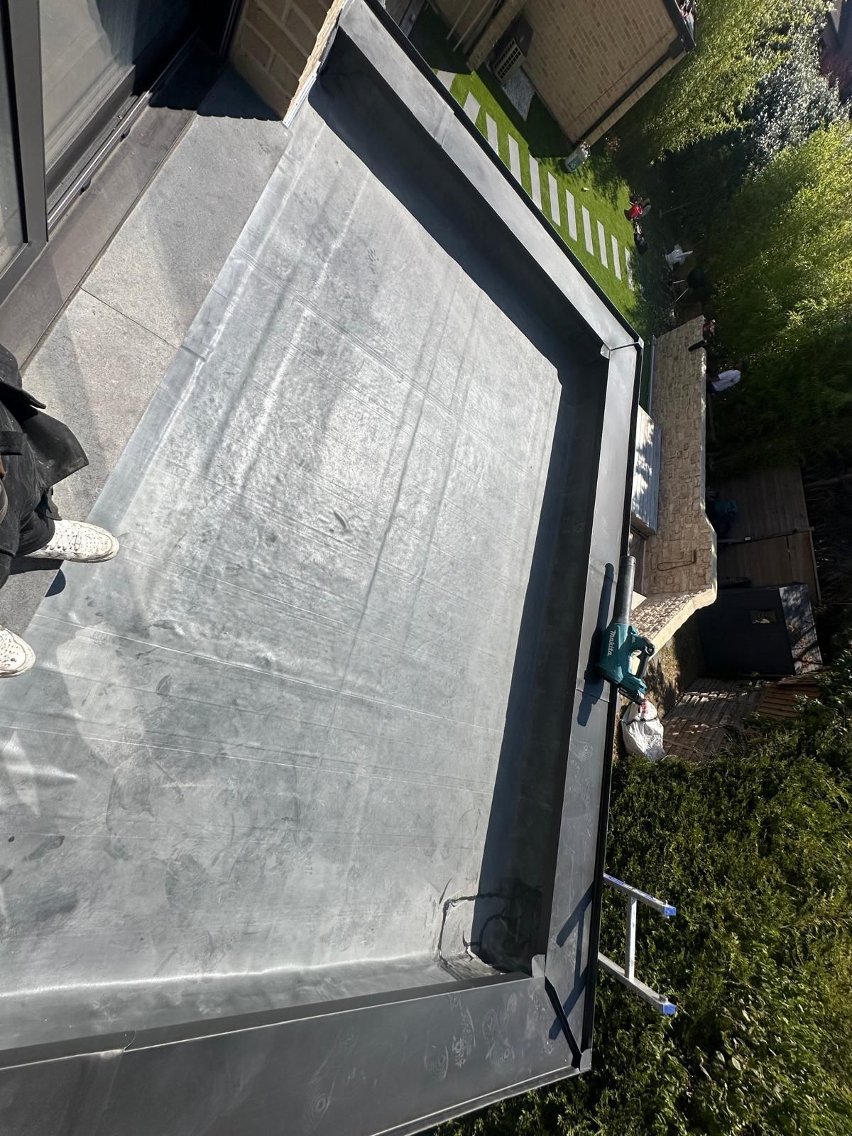 Application d'un mastic noir sur un matériau de toiture gris.