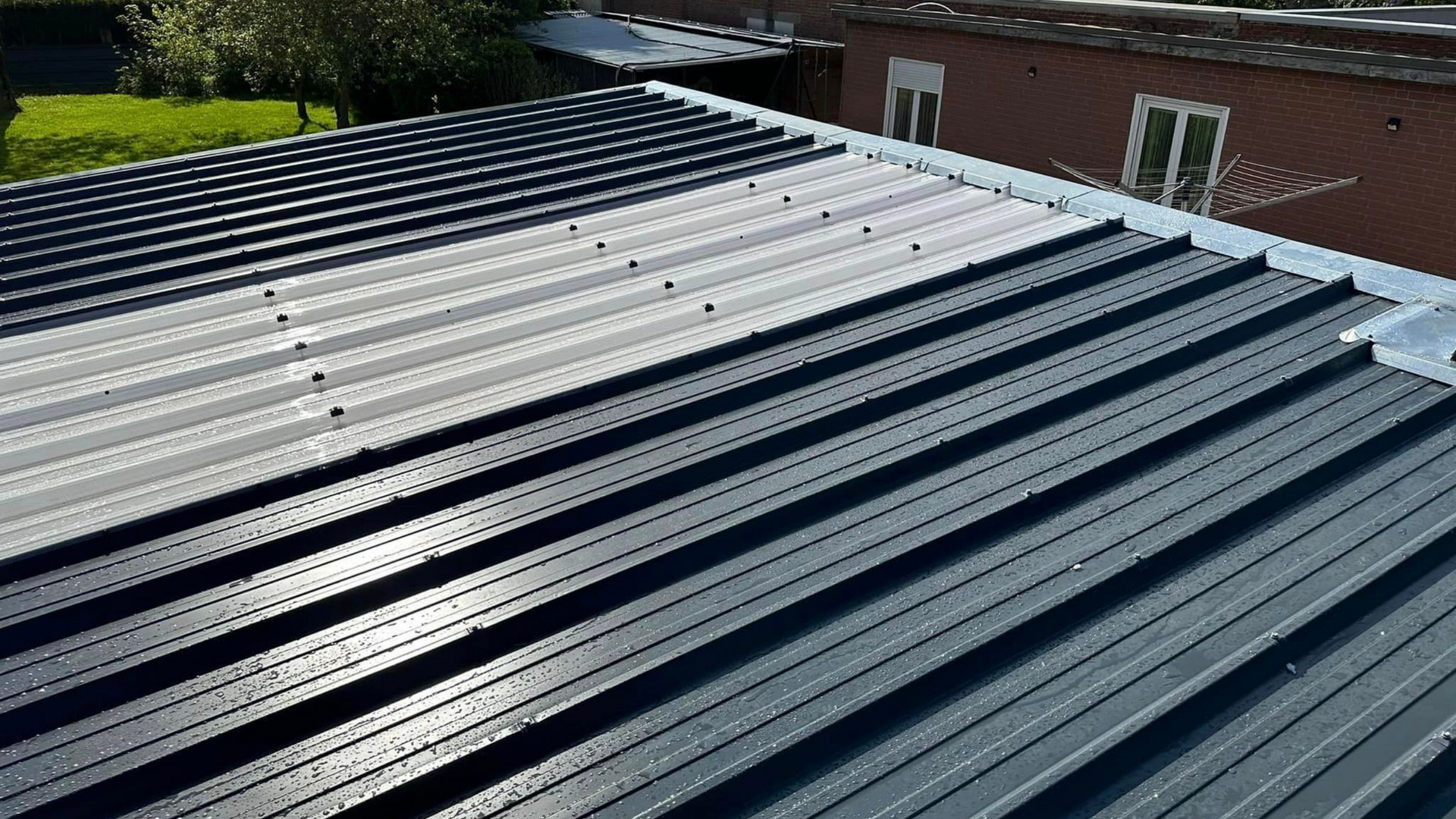 Couvreur travaillant sur un toit en métal bleu, en extérieur.