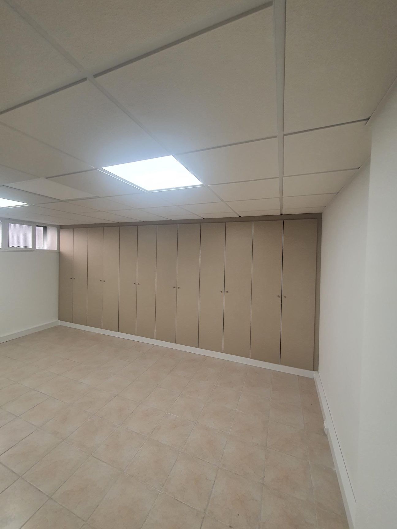 Uma grande sala vazia com piso de cerâmica e paredes brancas.