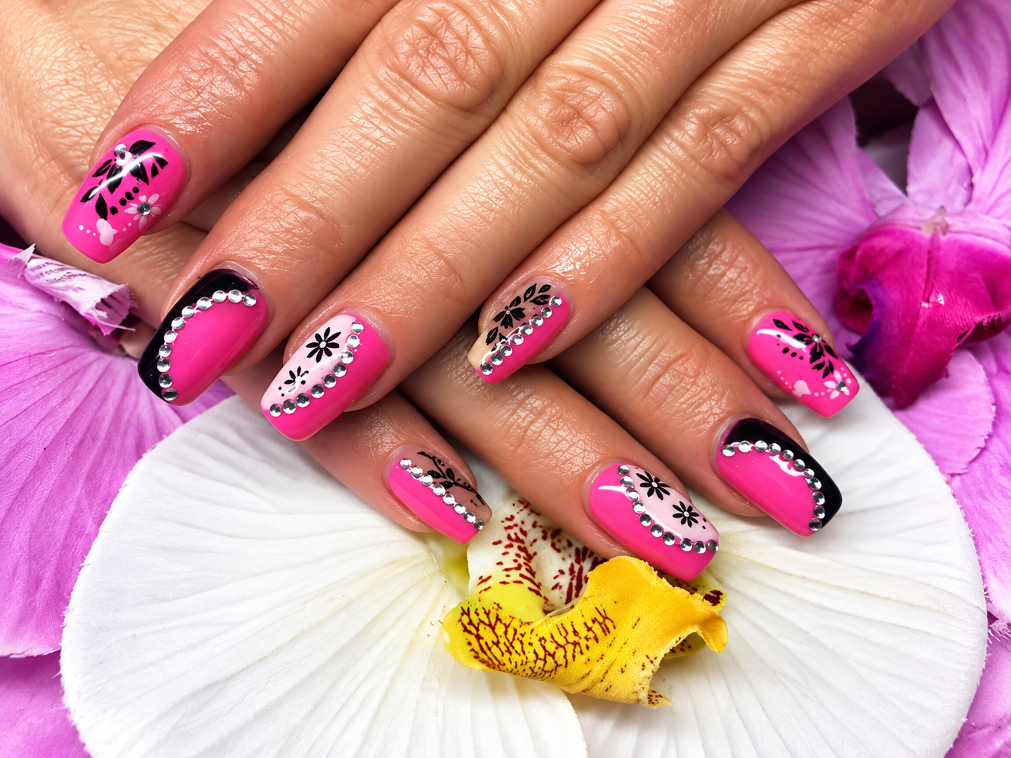 Pinkfarbenes Nageldesign mit schwarz-weißen Blumenmotiven auf weißen Orchideenblütenblättern
