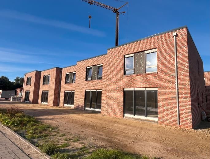 Modernes Backstein-Wohnhaus mit großen Fenstern und einem Kran darüber unter einem klaren blauen Himmel