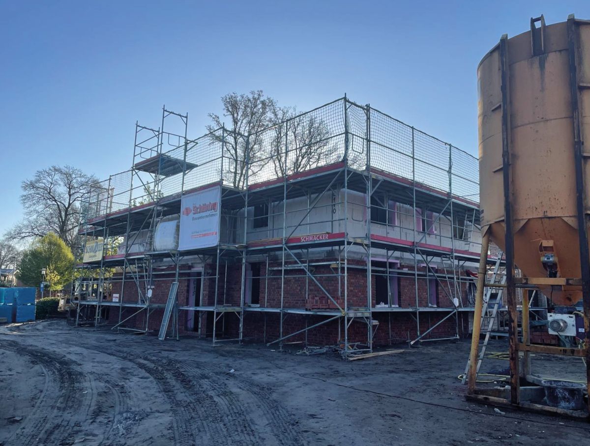 Eine Reihe moderner Backstein-Stadthäuser mit gepflasterten Gehwegen und kleinen Vorgärten an einem bewölkten Tag