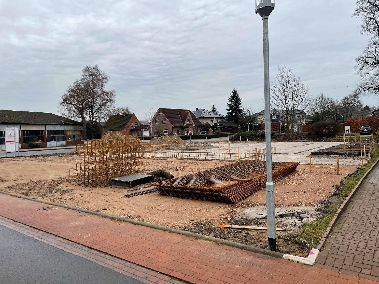 Unbebautes, landschaftlich gestaltetes Grundstück mit Ziegelsteinumrandungen, Kieswegen und einer Laterne in einem Wohngebiet