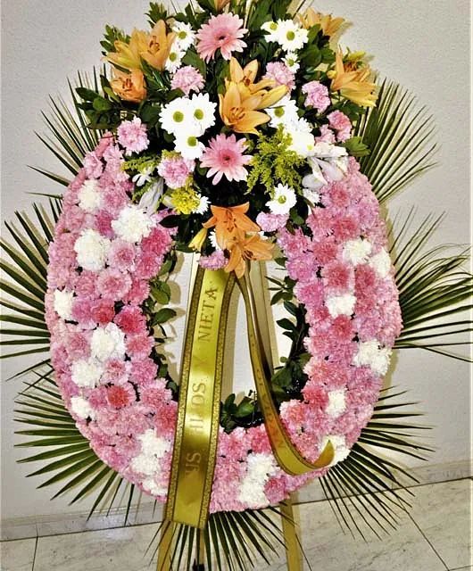 Una corona de flores rosas y blancas con una cinta que dice meta