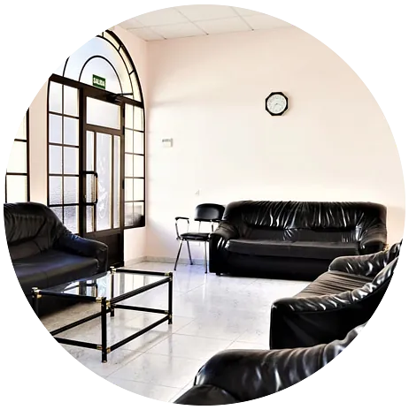 Una sala de estar con muebles negros y un reloj en la pared.