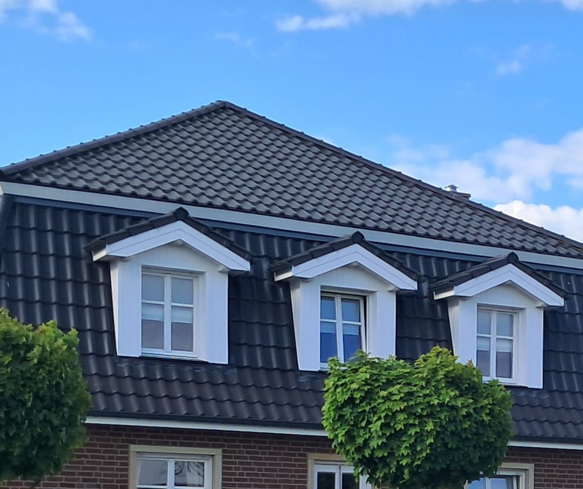 Ein Haus mit einem roten Ziegeldach und schwarzen Fensterläden