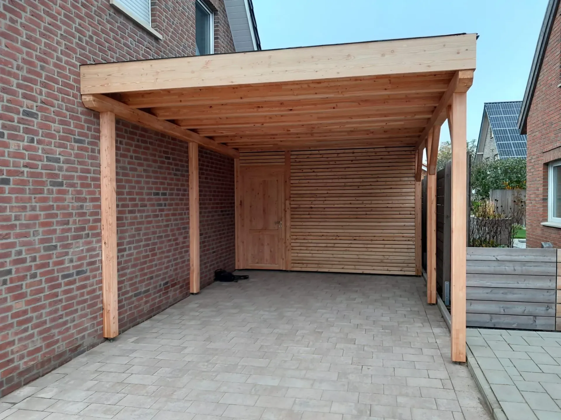 Ein Holzcarport ist an einem Backsteingebäude befestigt