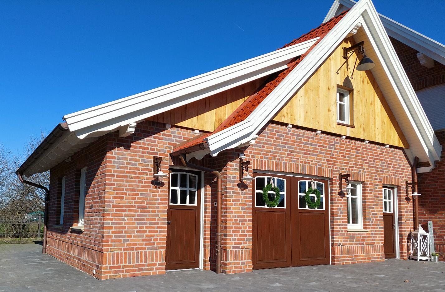 Ein Backsteinhaus mit Holzdach und braunen Garagentoren