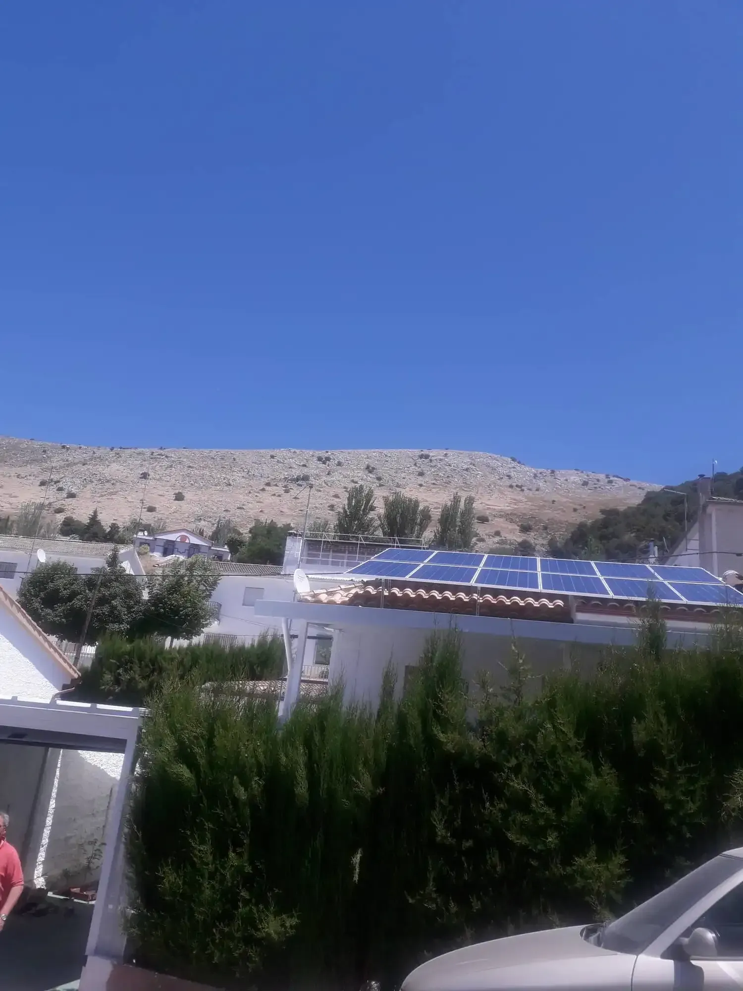 Edificios blancos con paneles solares en una soleada ladera desértica bajo un cielo azul despejado.