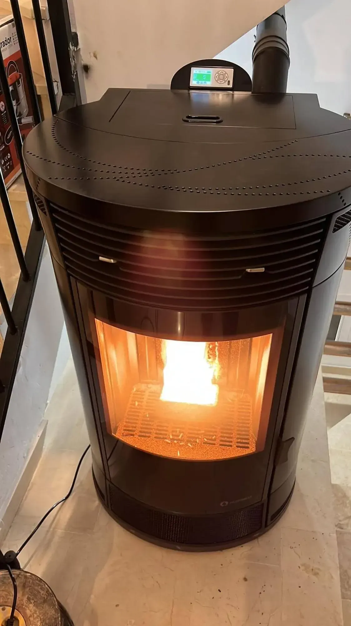 Estufa de pellets negra con fuego encendido en una habitación, vista desde arriba.