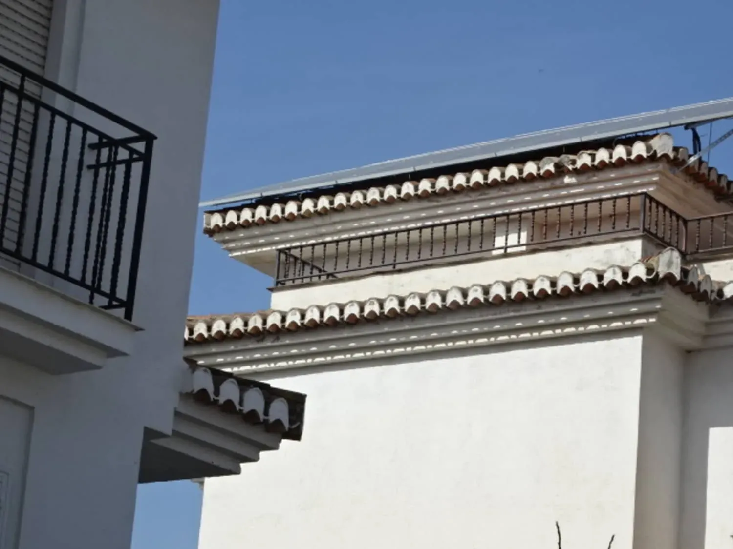 Tejados blancos de edificios con detalles decorativos de tejas contra un cielo azul