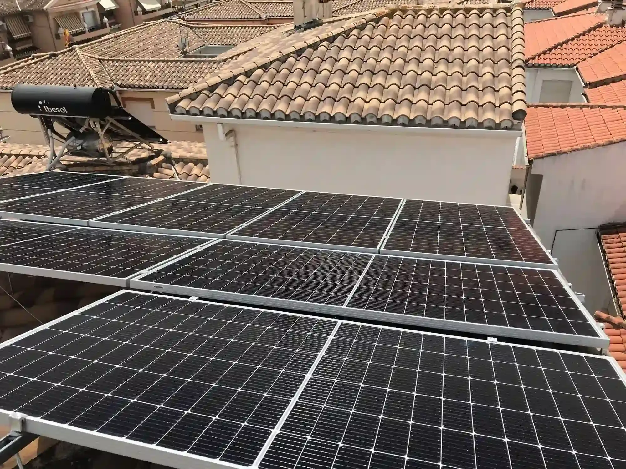 Paneles solares instalados en el tejado de una casa con tejas, bajo la luz del día.