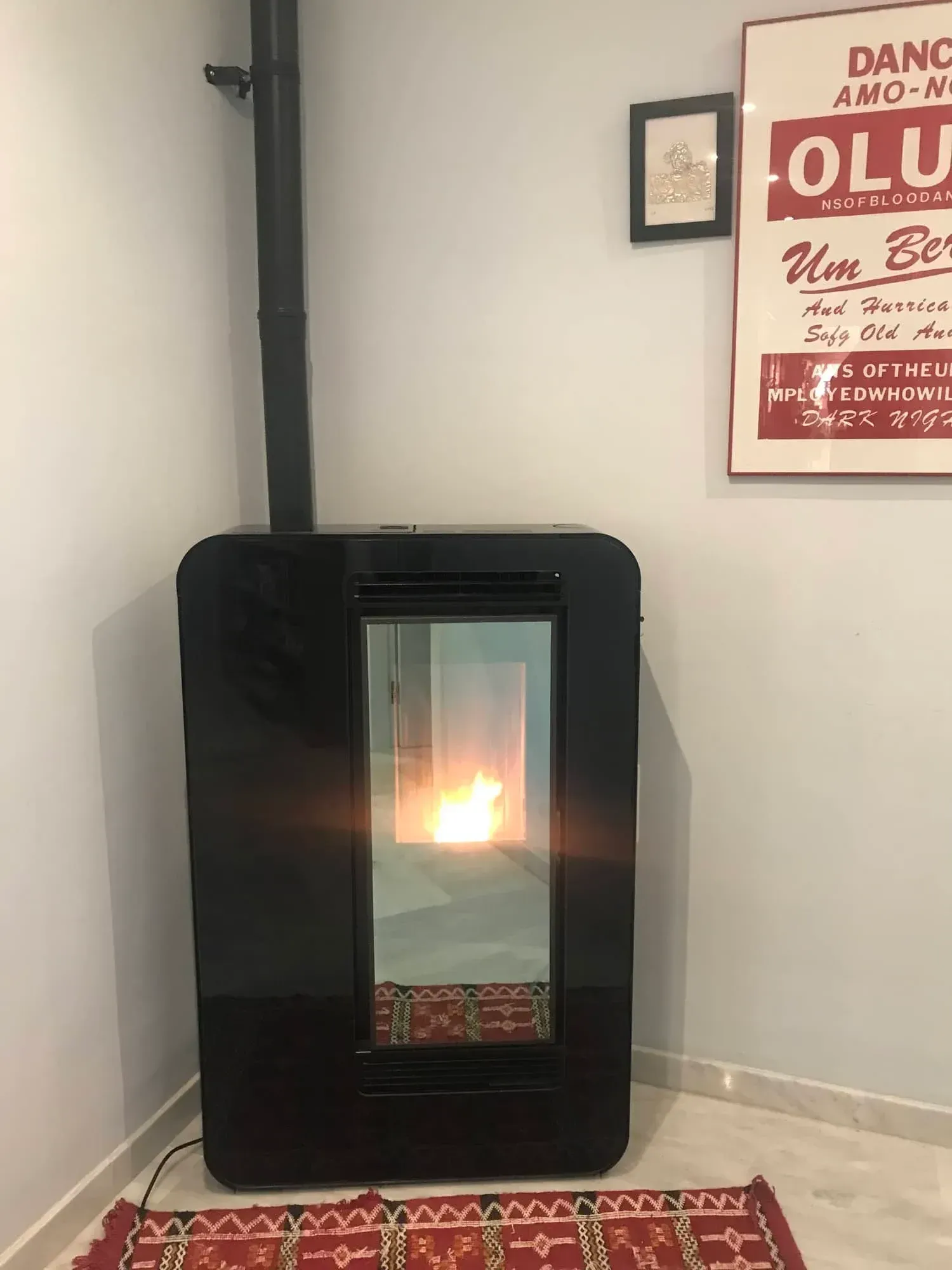 Chimenea eléctrica independiente de color negro que brilla en una esquina con un cuadro enmarcado 