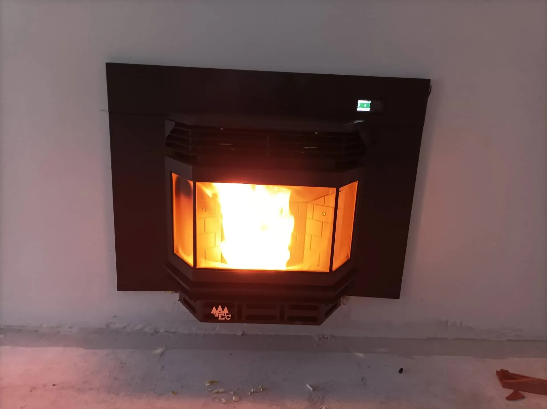 Chimenea empotrada en la pared, iluminada con un brillo anaranjado en la habitación.