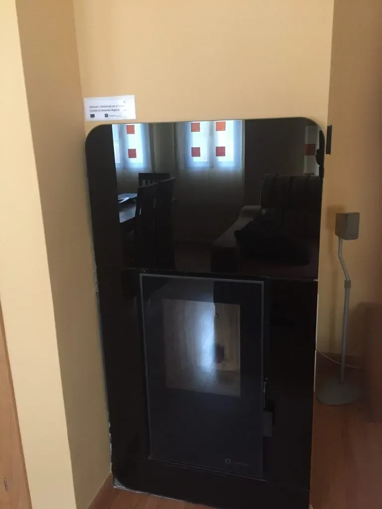 Parte frontal de cristal negro de una chimenea o calefactor de pared en una habitación de color beige