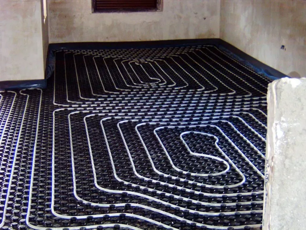 Tuberías de calefacción por suelo radiante instaladas en una habitación antes de que se termine el suelo.