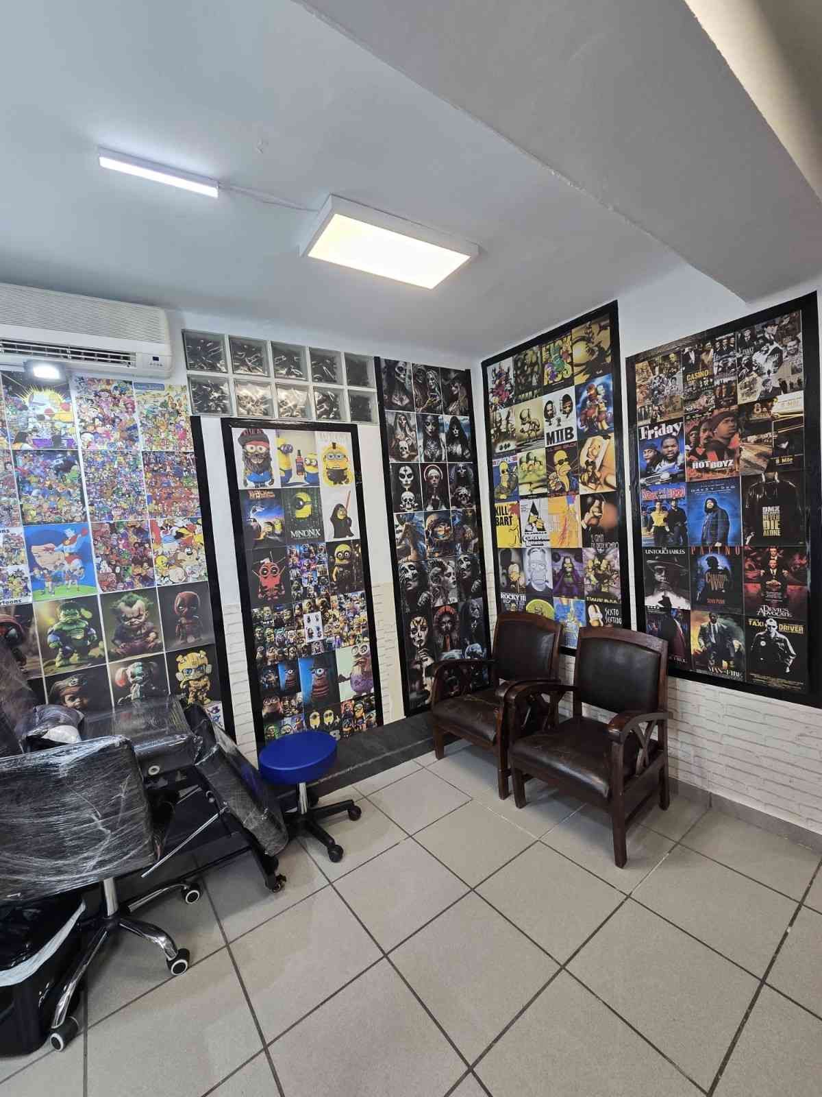 Interior de una tienda de tatuajes con paredes cubiertas de arte flash, dos sillas marrones