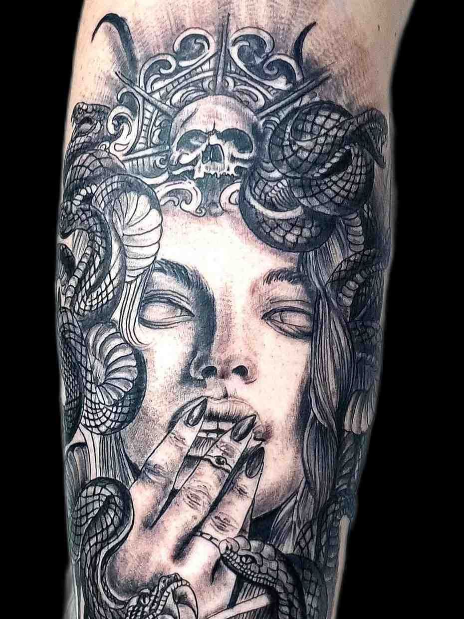 Tatuaje negro y gris de una figura con cabello de serpiente, una corona de calavera y una mano cubriendo la boca 