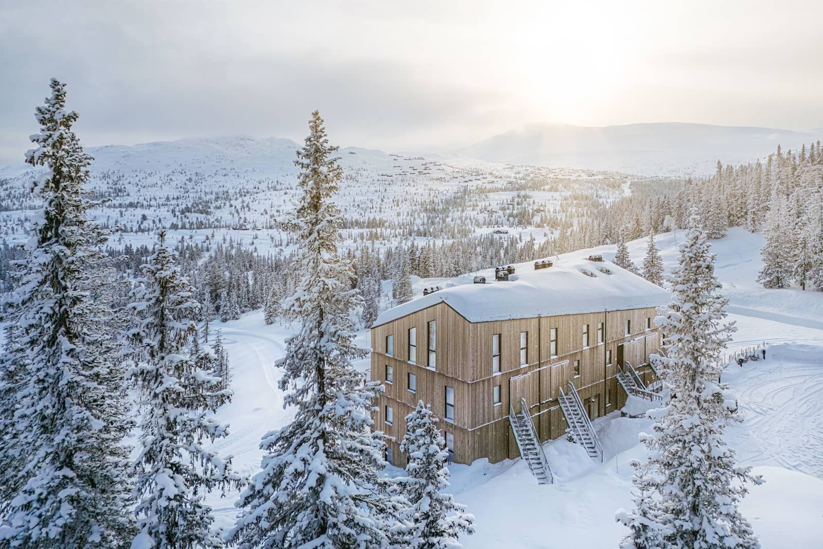 Eine Luftaufnahme eines Hauses inmitten eines verschneiten Waldes.