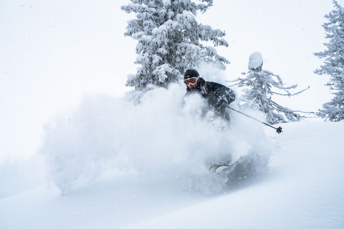 Eine Person fährt mit Skiern einen schneebedeckten Hang hinunter.