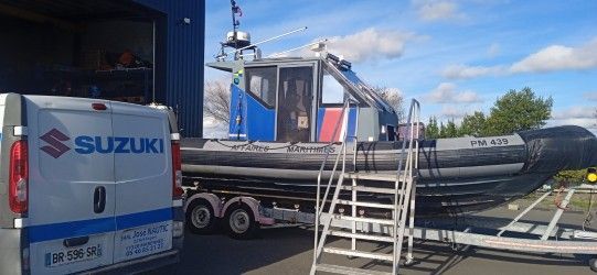 Un camion Suzuki bleu tractant un bateau pneumatique noir