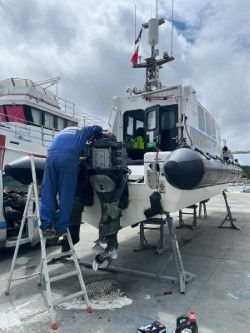 Une personne en salopette bleue travaille sur un petit bateau sur une remorque