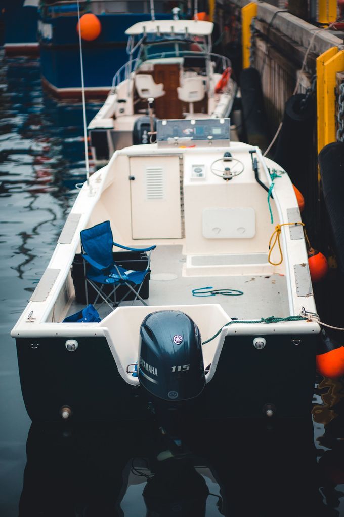 Petit bateau à moteur blanc amarré dans un port étroit