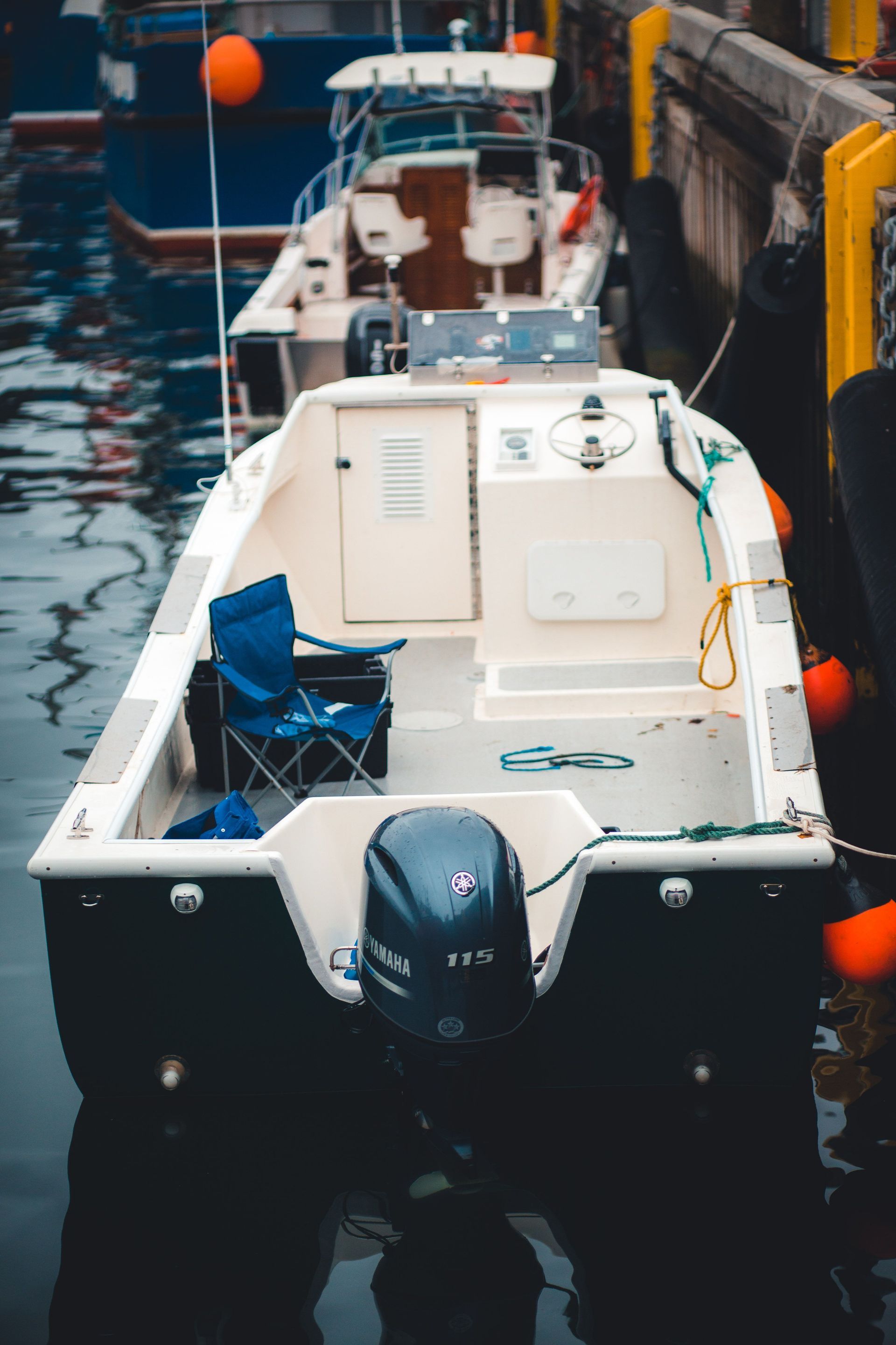 Petit bateau à moteur blanc amarré dans un port étroit, avec un moteur hors-bord