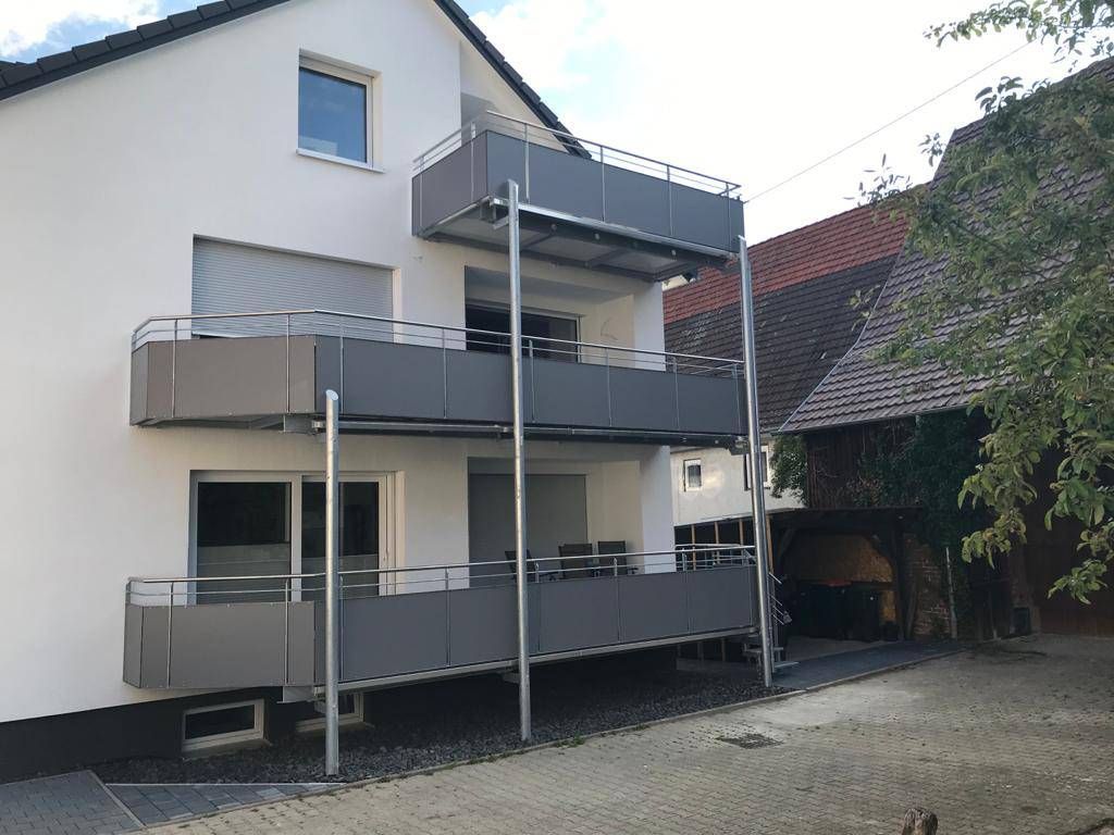 ein weißes Haus mit einem grauen Balkon davor