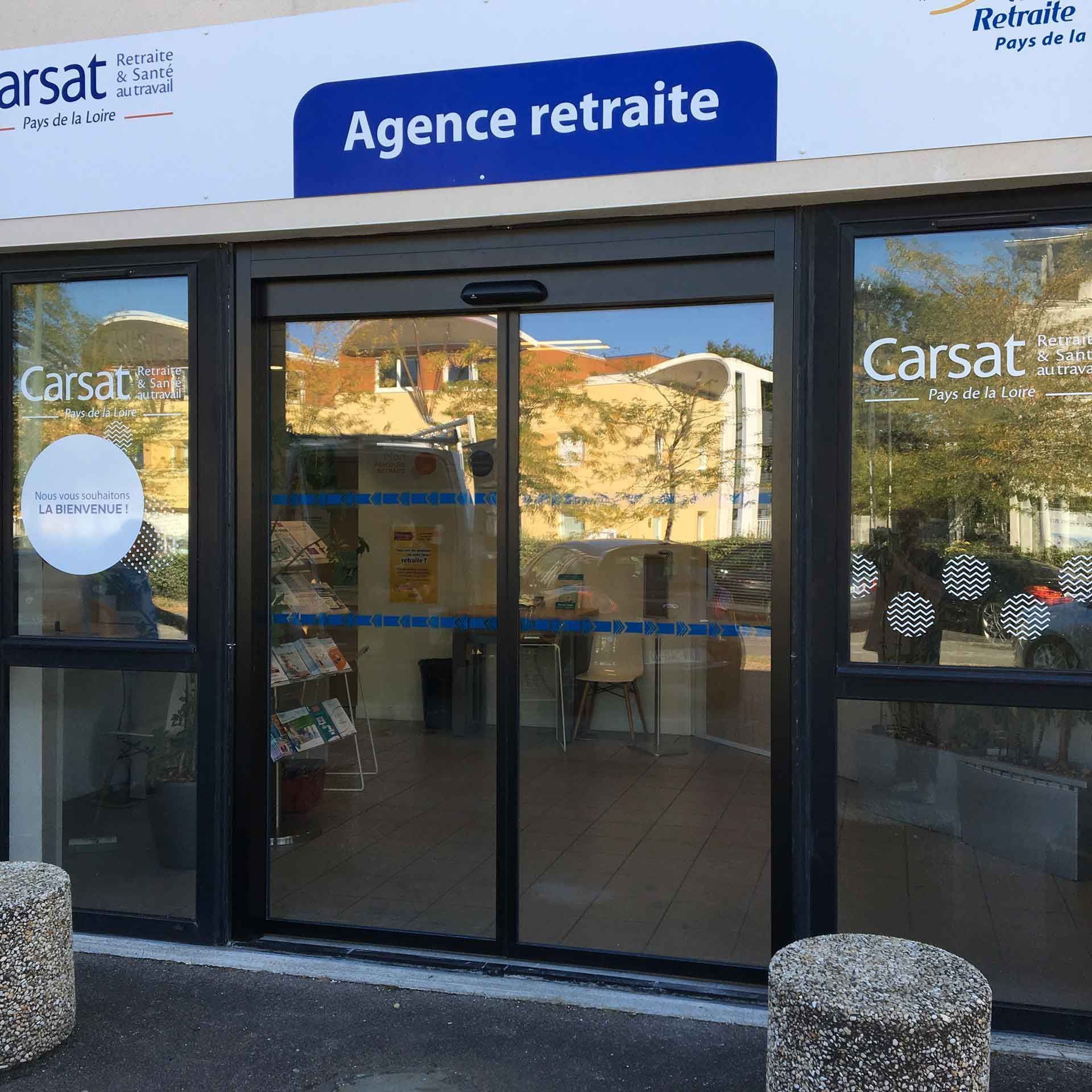 Entrée vitrée d'une agence de retraite Carsat avec enseigne bleue, portes coulissantes automatiques et intérieur carrelé.