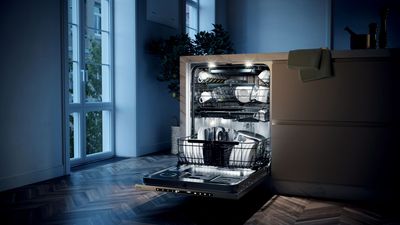 Plan de travail de cuisine avec centrifugeuse, bouilloire, mixeur plongeant et multicuiseur, avec un micro-ondes en arrière-plan.