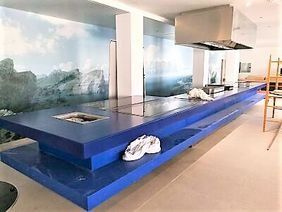 Cocina moderna con una gran isla azul y un mural de montaña en la pared.