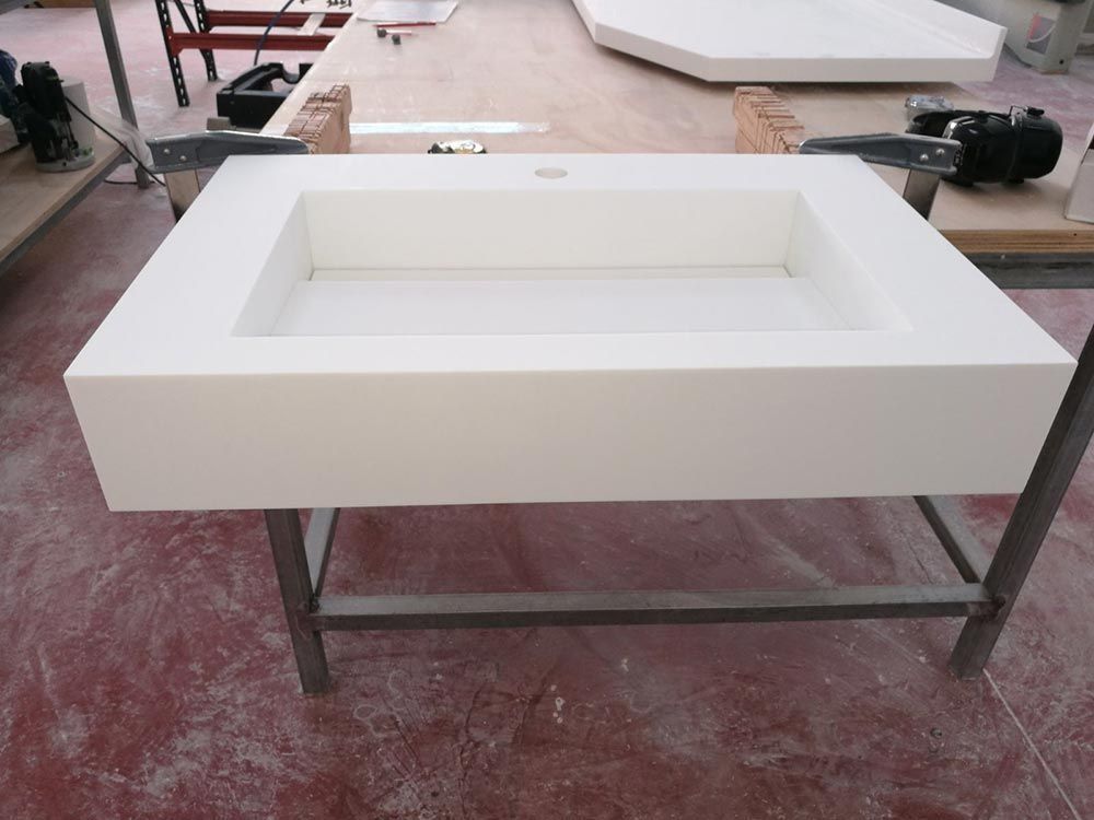 Lavabo rectangular blanco sobre un soporte de metal en un taller.
