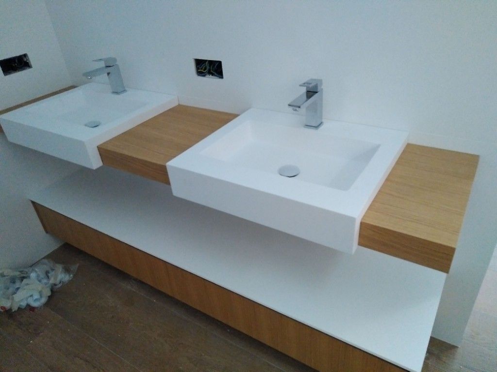 Tocador de baño moderno con dos lavabos blancos, grifería cromada y detalles de madera.