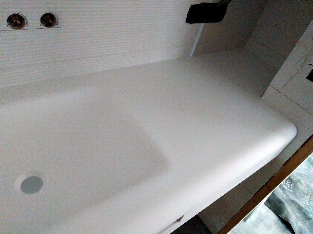 Bañera blanca en un baño con desagüe y orificios para grifo, vista desde arriba.