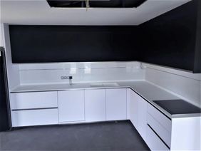 Cocina moderna en blanco y negro con gabinetes blancos y encimeras oscuras en una habitación vacía.