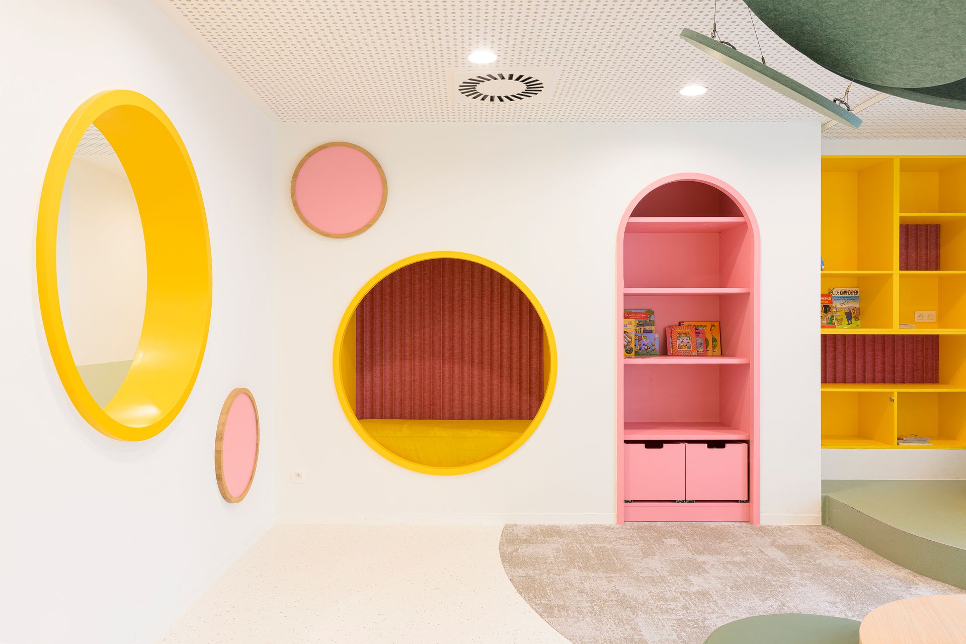 Lichte speelkamer in pastelkleuren met cirkels met gele randen, roze wandplanken en een gebogen, modern wandontwerp