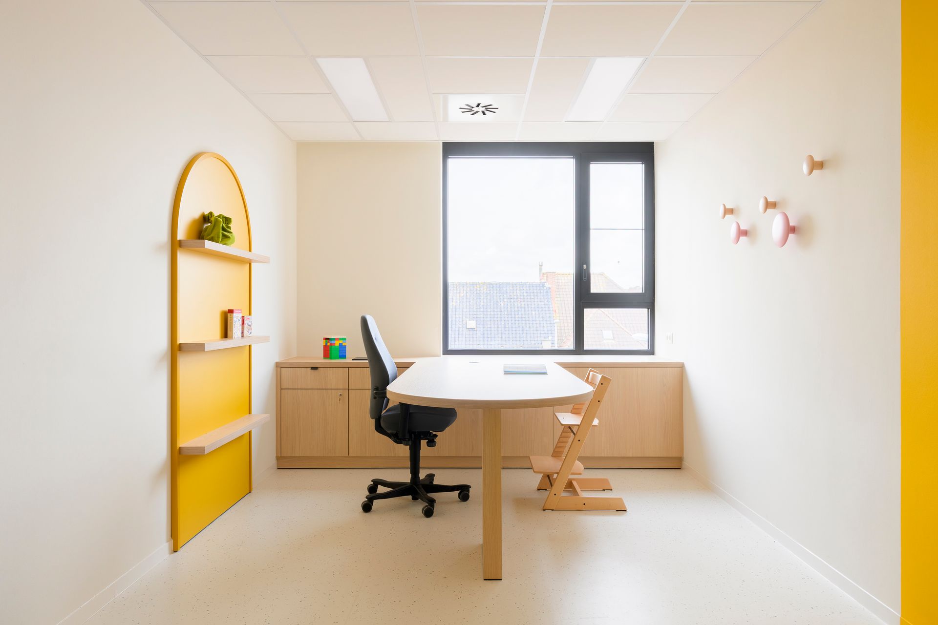 Minimalistisch kantoor met een bureau, stoel, gele plank en groot raam in een lichte, witte kamer