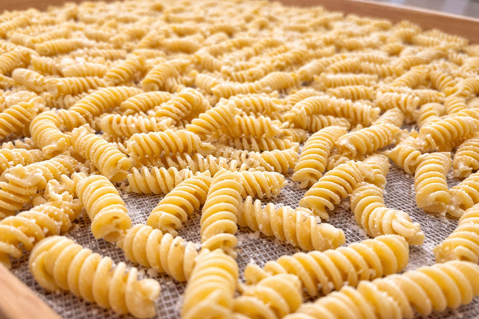 Gnocchi mit Tomatensoße, Basilikum und Parmesan auf einem weißen Teller, mit Brot, Tomaten, Gabel und Messer auf einem Holztisch.