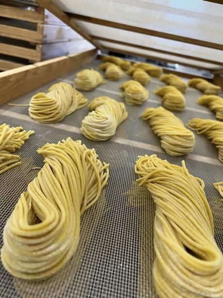 Frisch zubereitete gelbe Nudeln trocknen im Innenbereich auf einem Gitterrost.