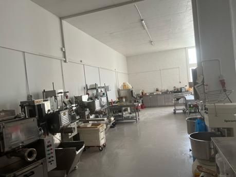 Eine hell erleuchtete Großküche mit Geräten und Vorbereitungsstationen aus Edelstahl.