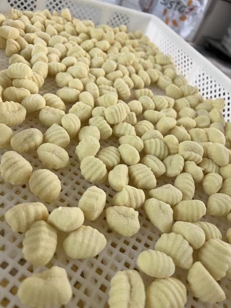 Frische, ungekochte Gnocchi-Nudeln auf einem weißen, geschlitzten Trockentablett.