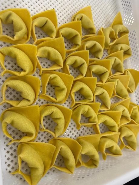 Frisch zubereitete gelbe Nudelquadrate, gefüllt und gefaltet in einer weißen Schale.