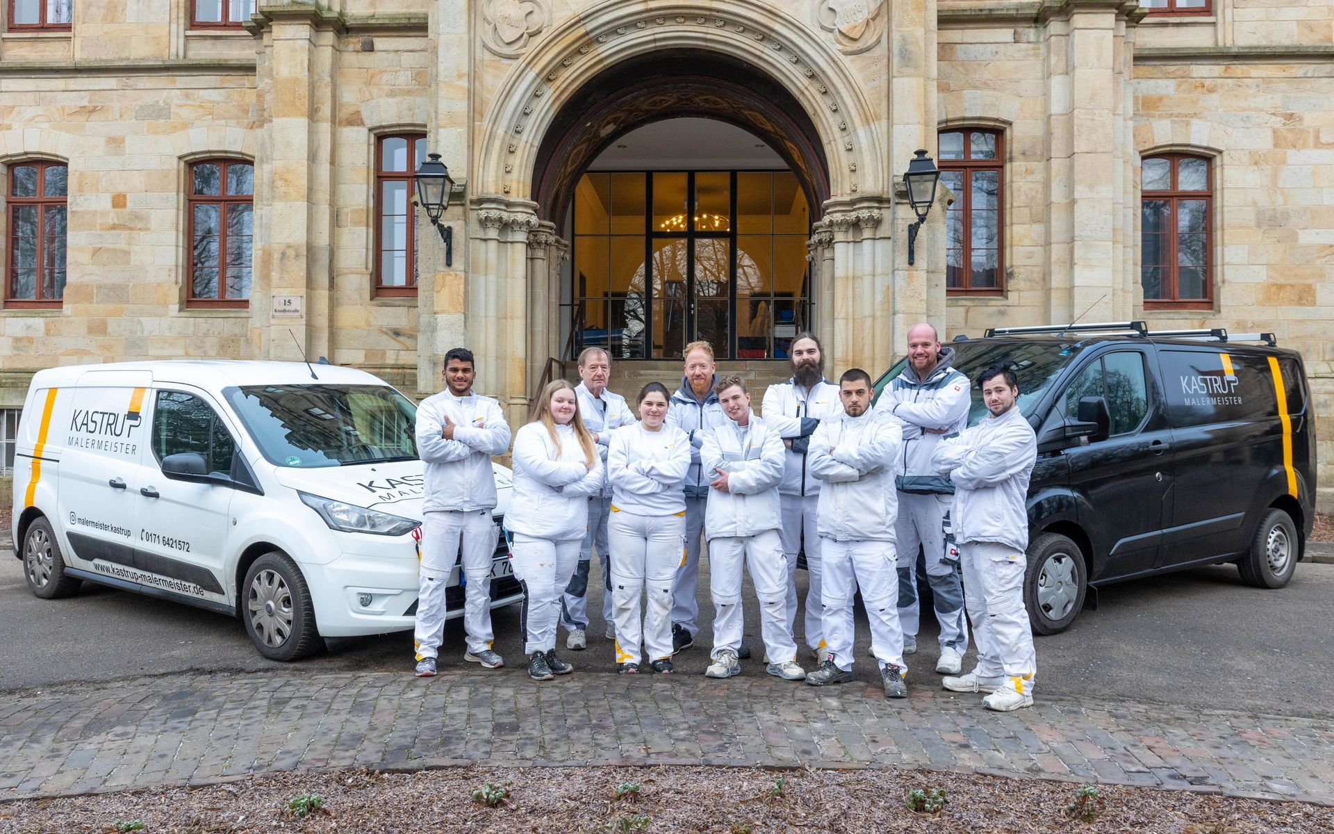 Eine Gruppe von Menschen posiert vor zwei Lieferwagen für ein Foto.