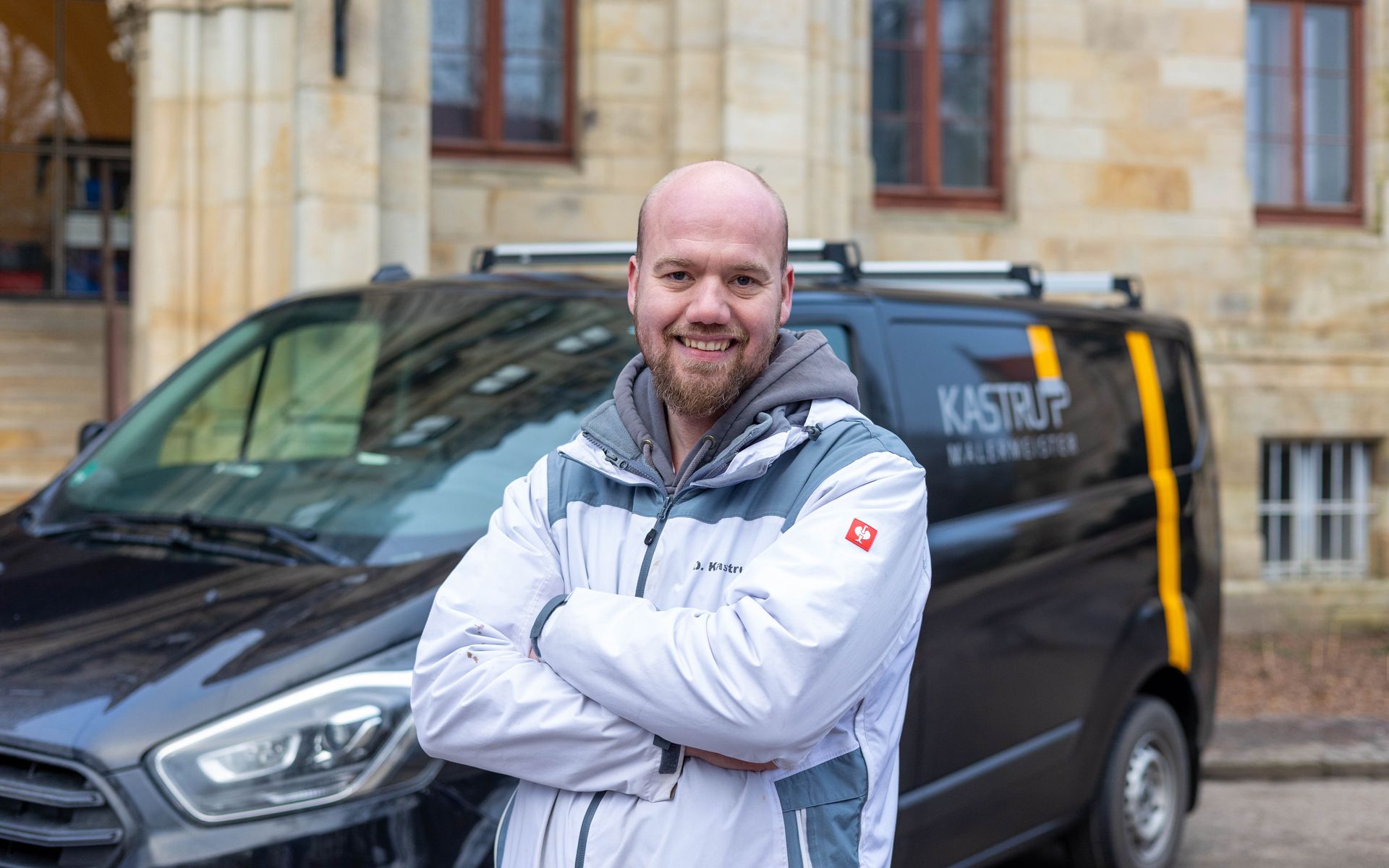 Ein Mann steht mit verschränkten Armen vor einem Lieferwagen.